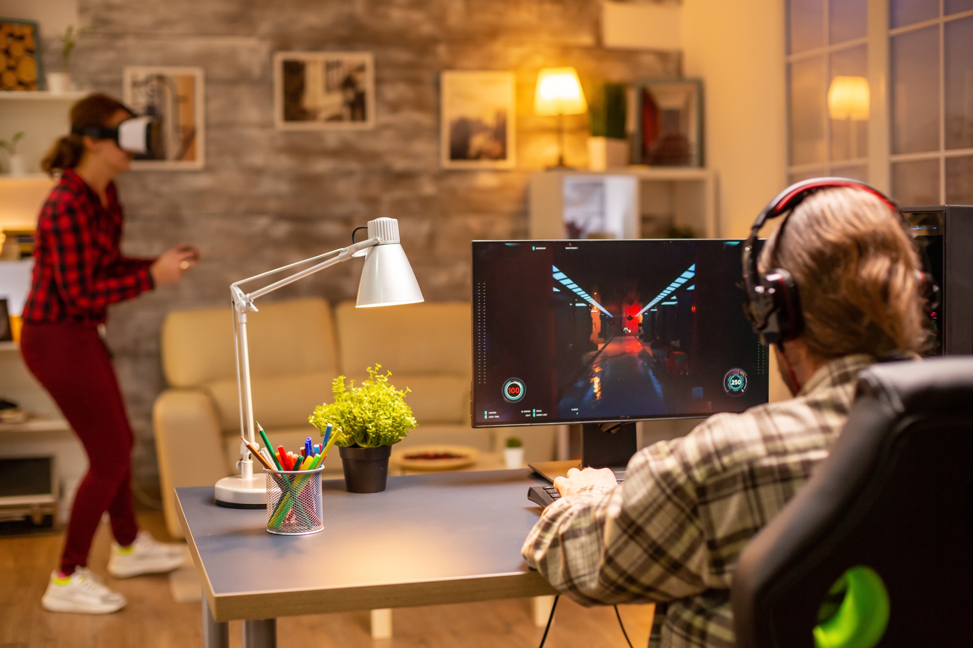 Back view of professional video gamer playing on powerful PC late at night in the living room